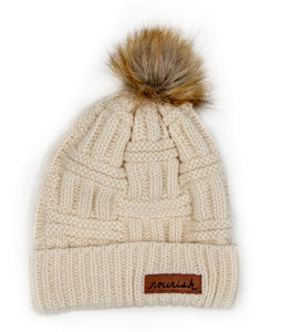 Ivory Cable Knit Hat with leather Nourish tag and a pom pom