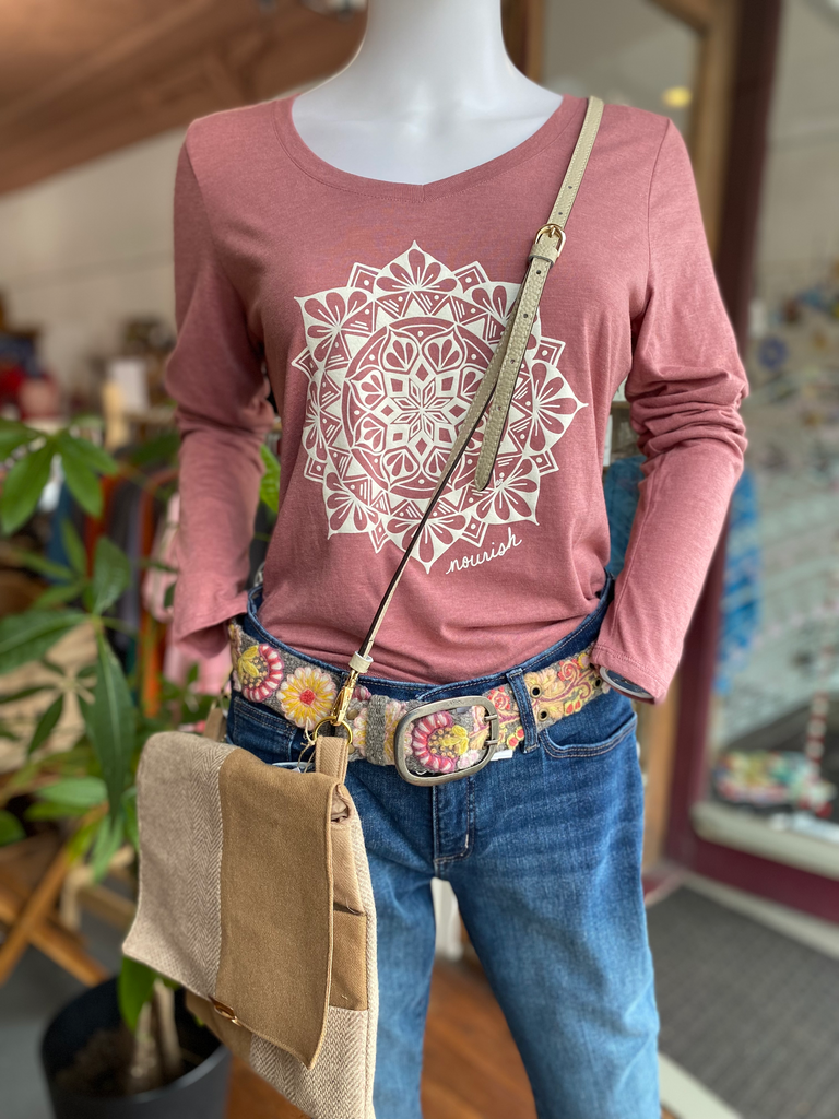 Image of the shirt displayed on a mannequin with blue jeans, fair trade belt and upcycled over the should bag.
